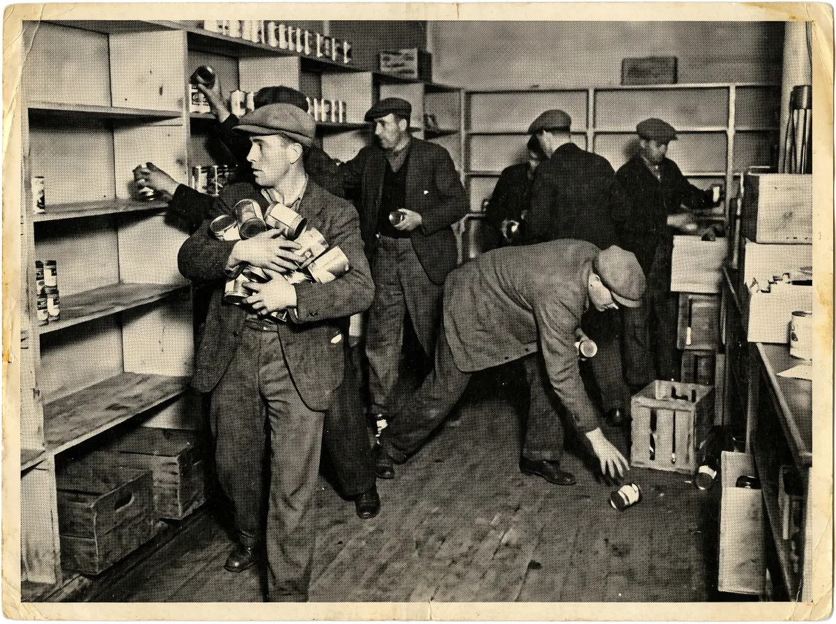 Men in mid-century clothing clearing a grocery shelf of canned goods, rendered as a vintage newspaper halftone