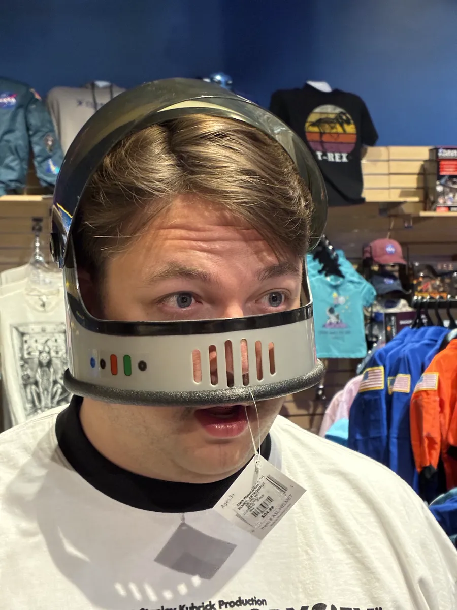 Thomas, the league's newest member, wearing a toy astronaut helmet in a gift shop, photographed as a vintage newspaper halftone
